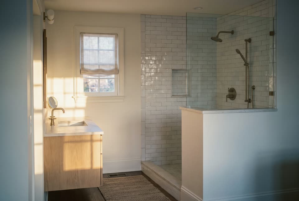 Illustration of a bathroom with a tiled walk-in shower and a white oak vanity in morning light